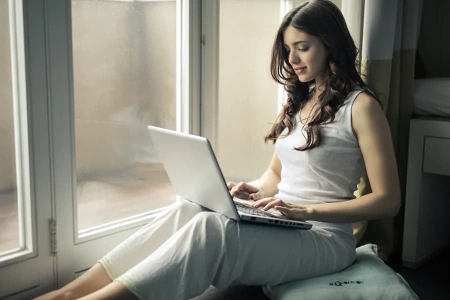 A person working at a laptop beside a window