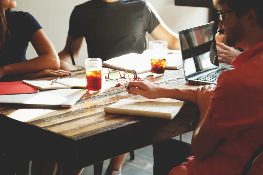 Colleagues meeting around a table with laptops