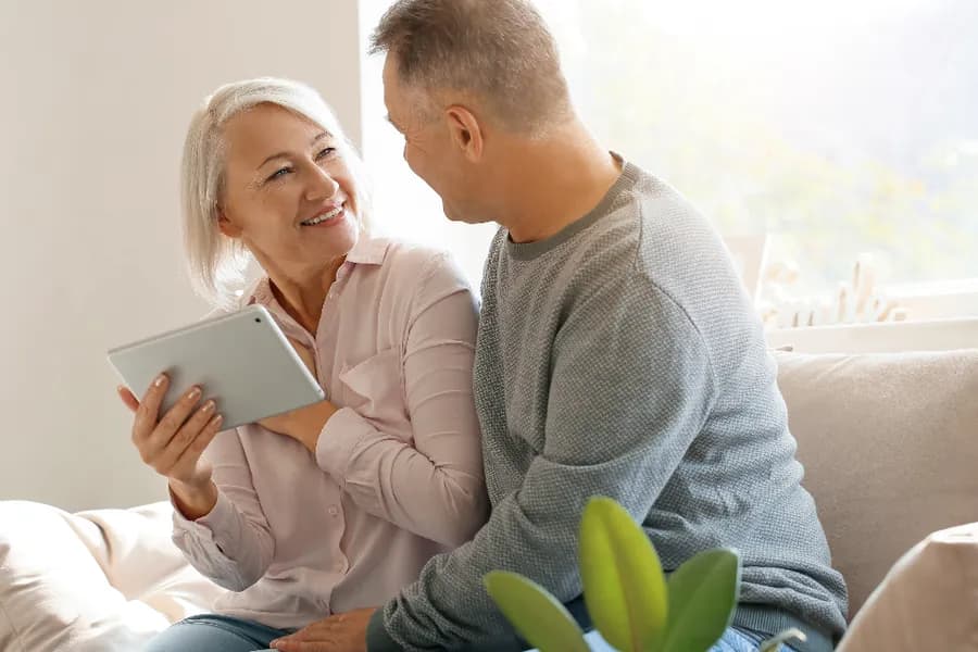 Two people sitting together at home looking at a tablet