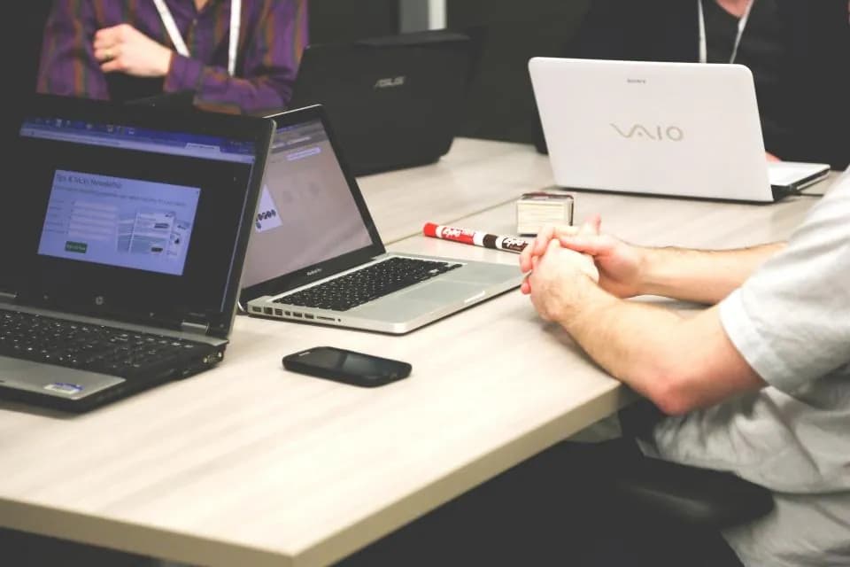 Two people sitting across a desk with laptops open between them