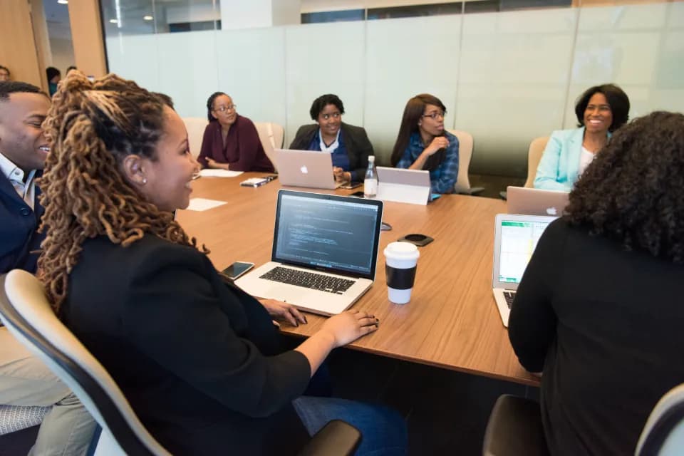People seated around a boardroom table with open laptops